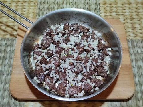 Добавить лук к мясу и обжарить все вместе еще 5 мин.