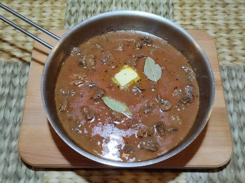 Влить к мясу полученный соус, добавить перец, лавровый лист, сливочное масло, подсолить по вкусу.