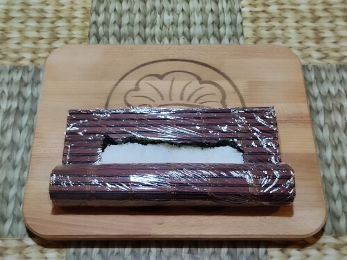 Приподнять край коврика и аккуратно скрутить ролл, придерживая начинку.