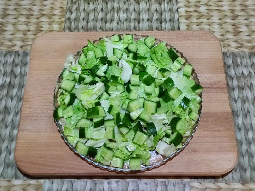 Огурцы нарезать кубиками распределить поверх салата.