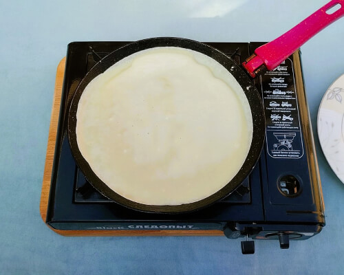 Налить тесто на сковороду, распределить по поверхности тонким слоем. Убавить огонь до среднего.